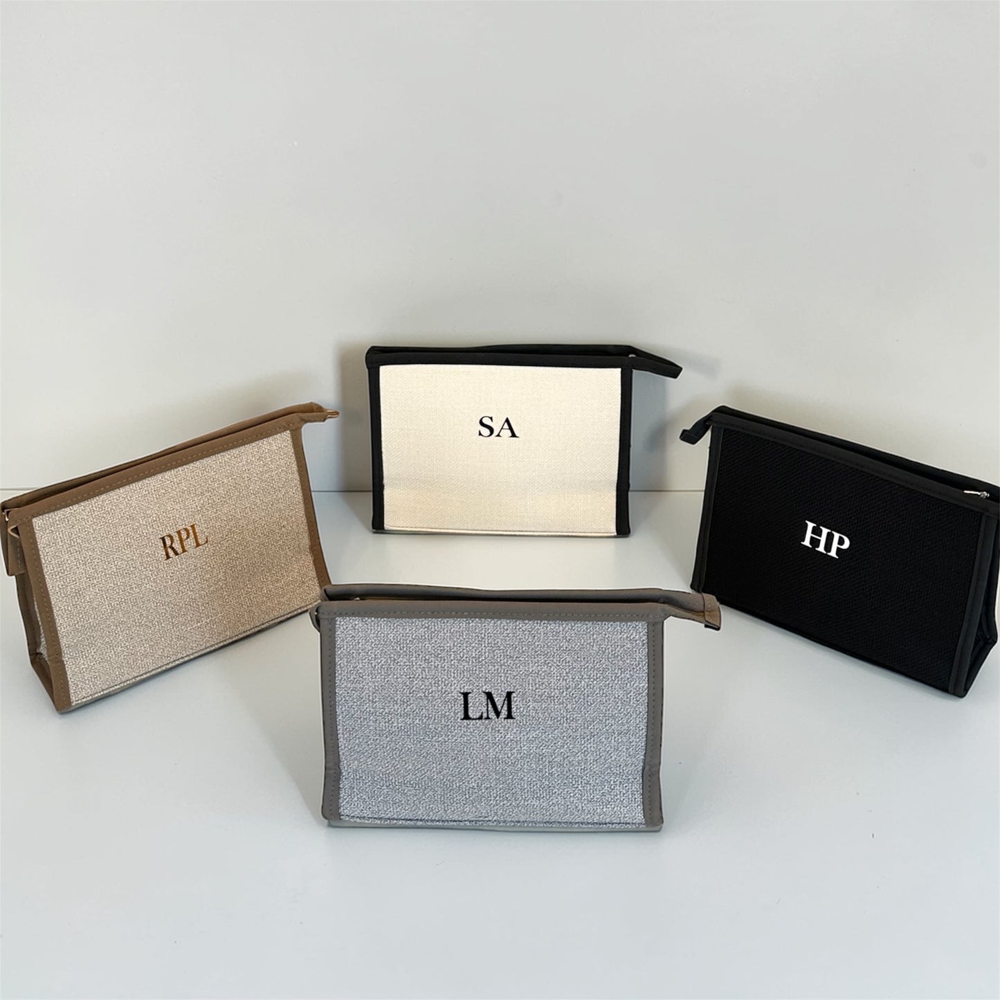 Four pouches with initials on a white background